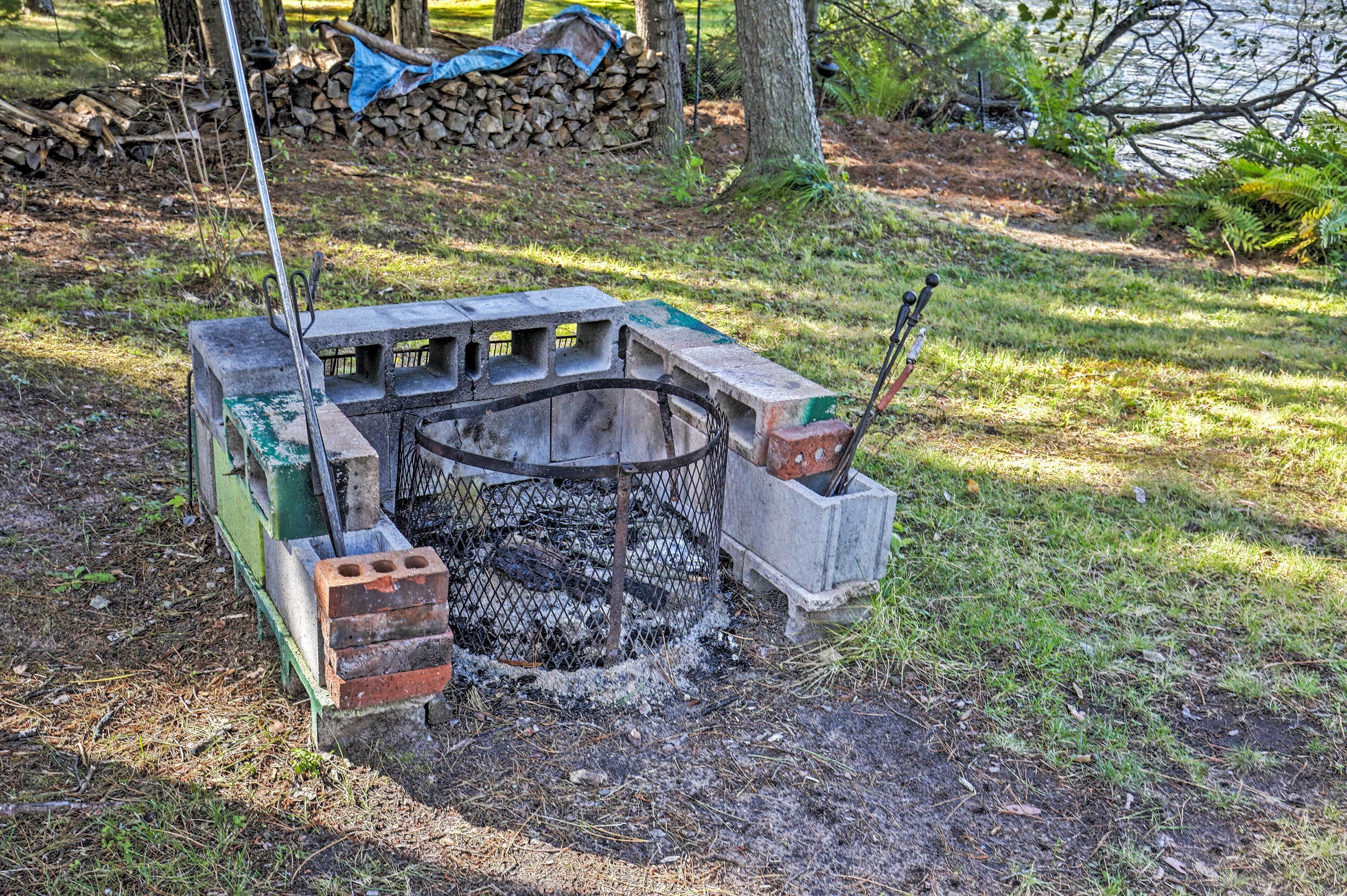Una parrilla de concreto al aire libre con base de ladrillo, rodeada de césped y árboles.