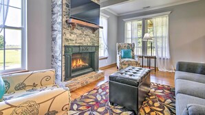 Un salon avec une cheminée en pierre, un canapé, un pouf et un fauteuil.