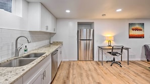 A modern kitchen with white cabinets, granite countertops, stainless steel appliances, and a wooden floor. - Denver Area Duplex w/ Patio: Walk to Park! (Arvada)