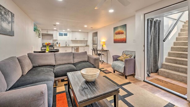 A modern living room with a sectional sofa, a coffee table, and a dining area in the background. - Denver Area Duplex w/ Patio: Walk to Park! (Arvada)