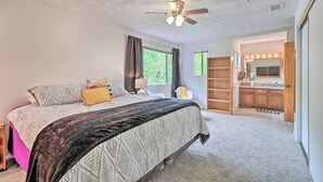 Une chambre à coucher avec un lit, un ventilateur de plafond, une coiffeuse avec un miroir et une fenêtre.
