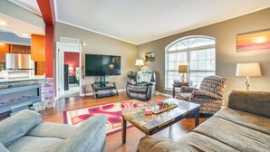 A living room with a TV, seating, and a kitchen area. - Serene Presque Isle Harbor Home on Sunrise Side! (Presque Isle)