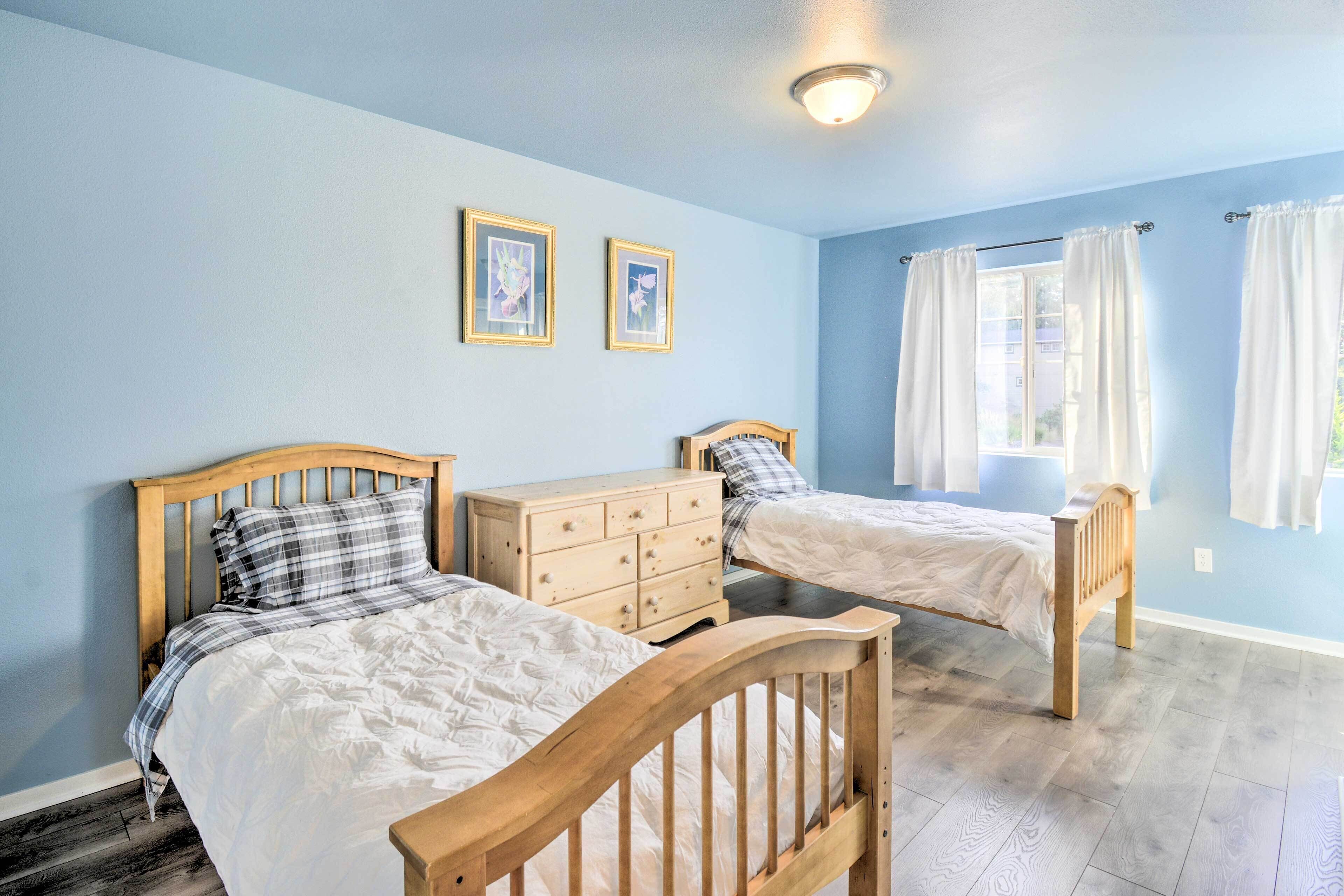 Une chambre à coucher avec deux lits en bois, une commode et une fenêtre avec des rideaux.