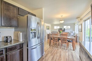 A modern kitchen with a large stainless steel refrigerator, wooden cabinets, and a dining area with a wooden table and chairs.