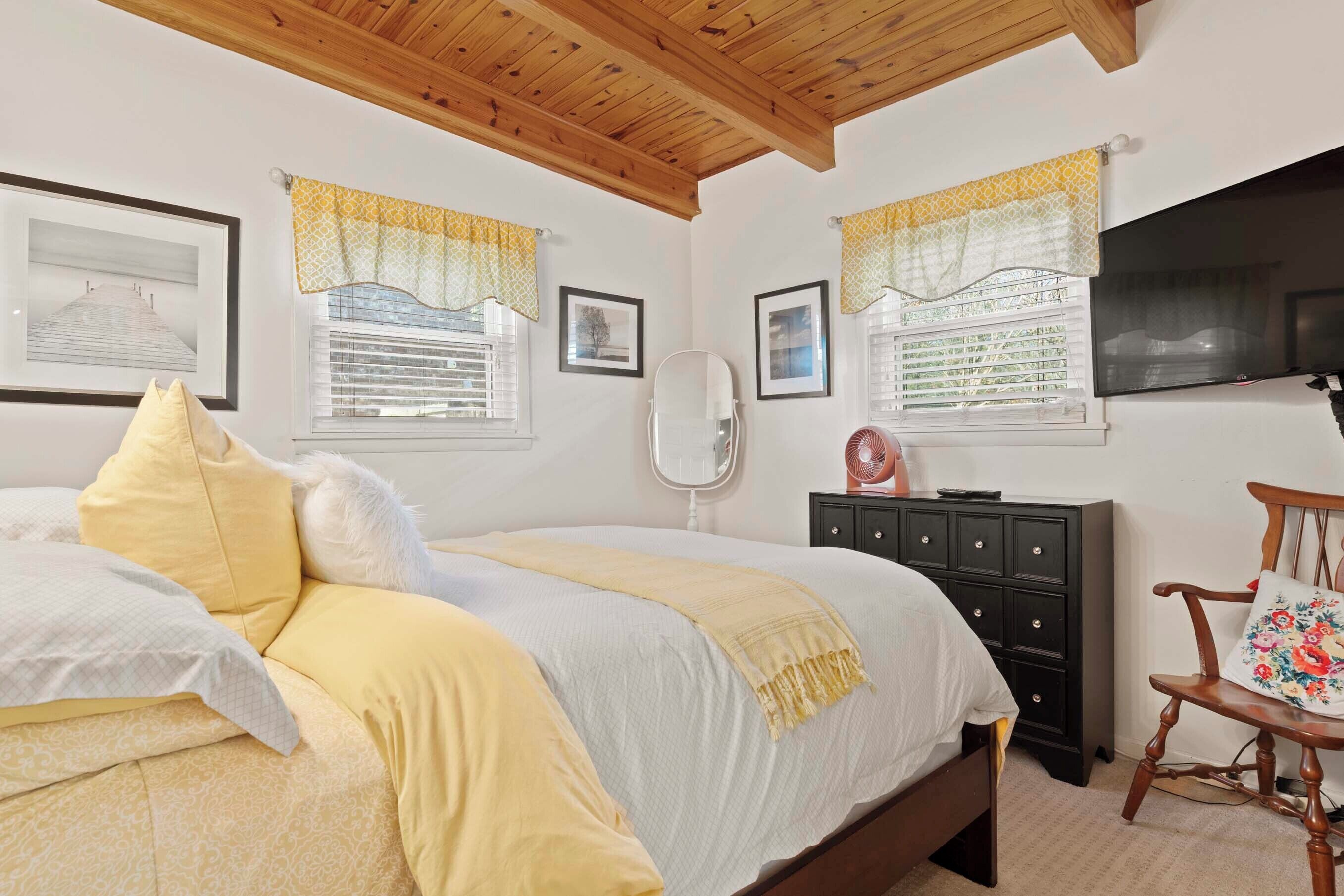 A bedroom with a bed, a dresser, a chair, and a TV.