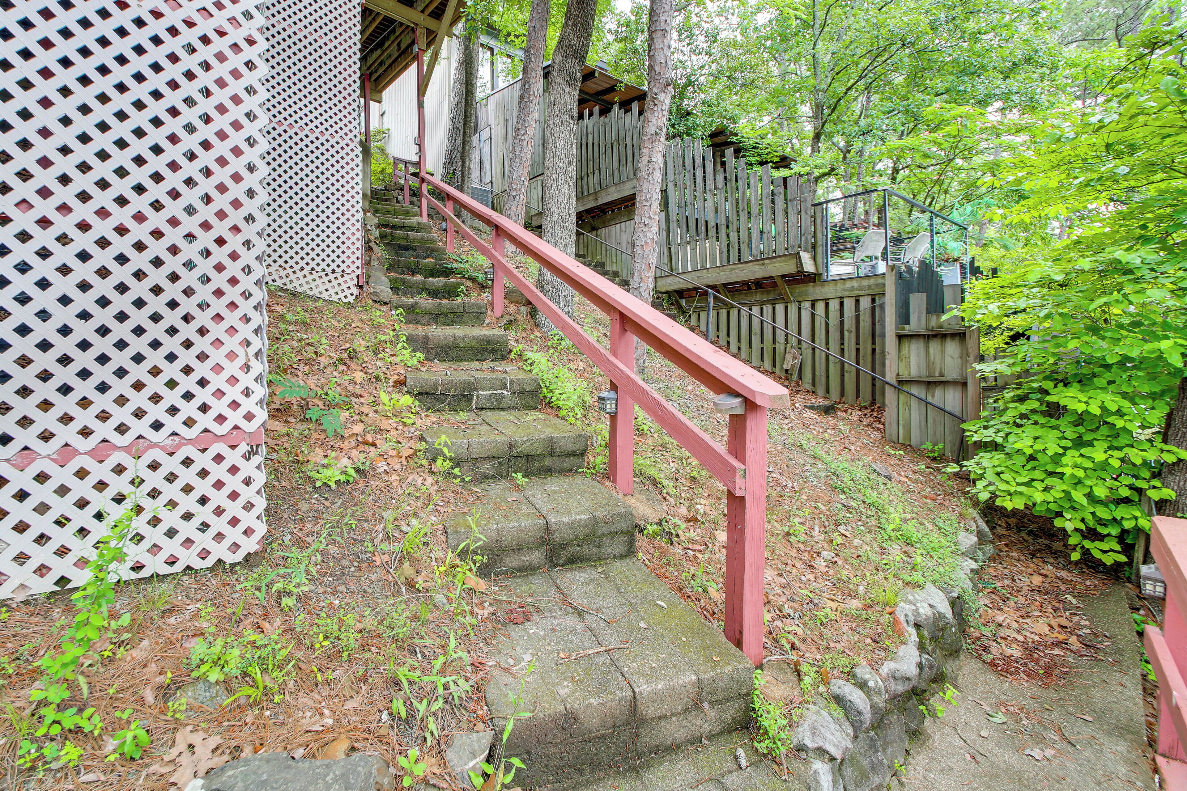 A set of stone steps with a red handrail leading to a wooden structure.