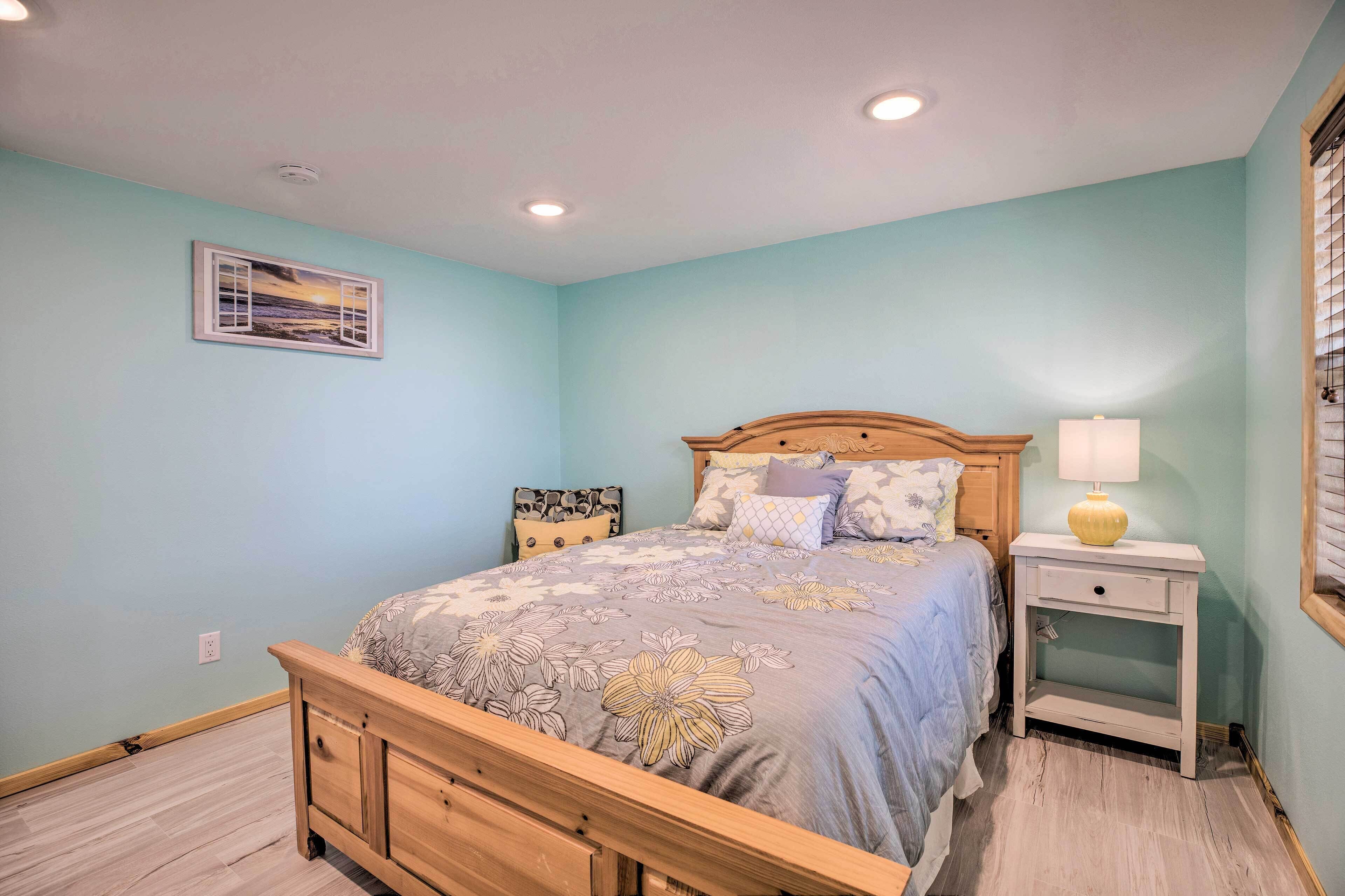 Un dormitorio con una cama, mesitas de noche y una lámpara fijada a la pared.