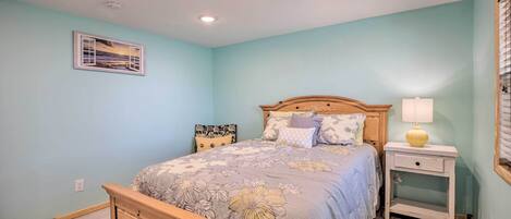 Un dormitorio con una cama, mesitas de noche y una lámpara fijada a la pared.