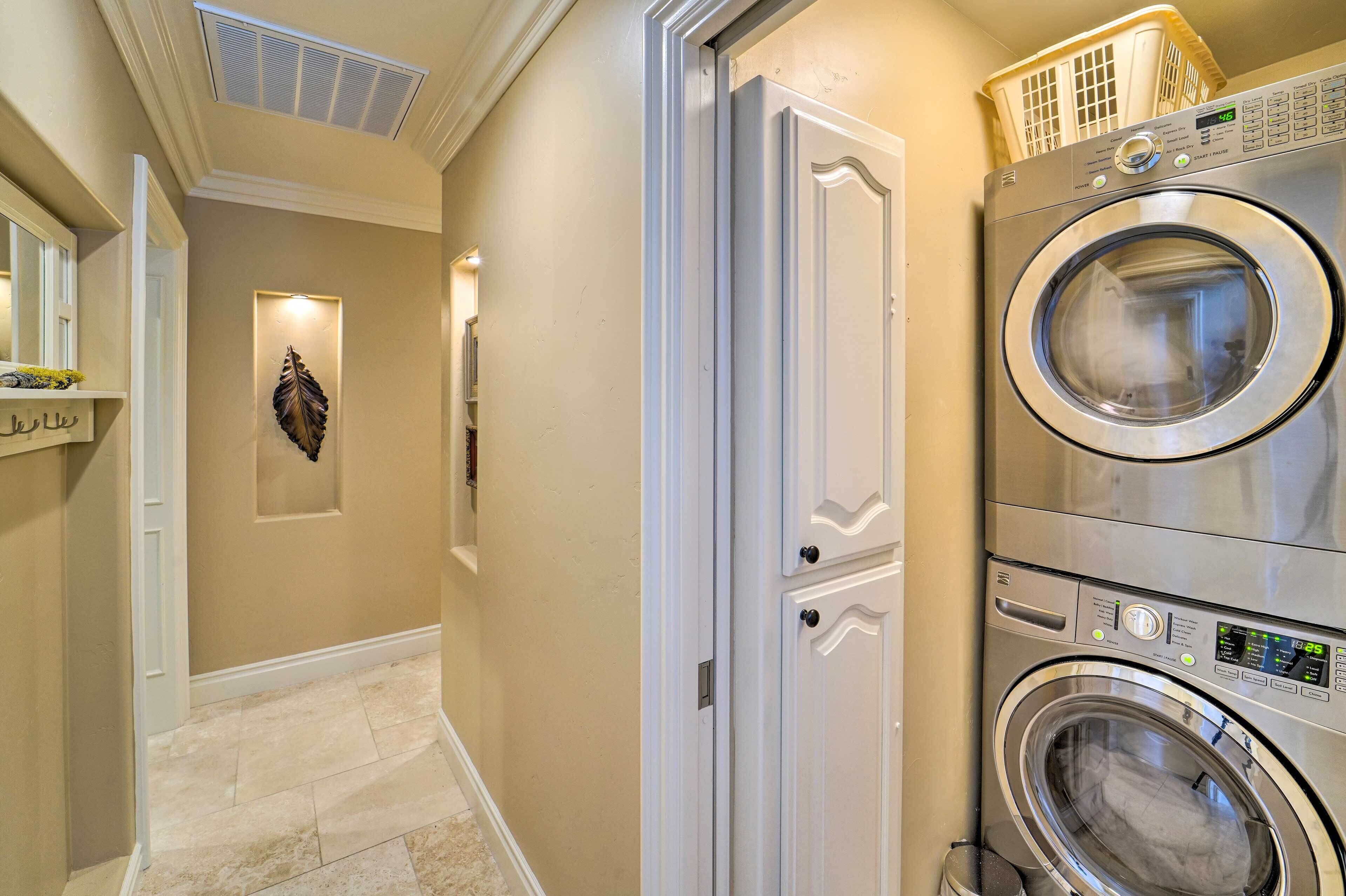 A laundry room with two stacked front-loading washing machines, a white door, and a wall-mounted decorative leaf.