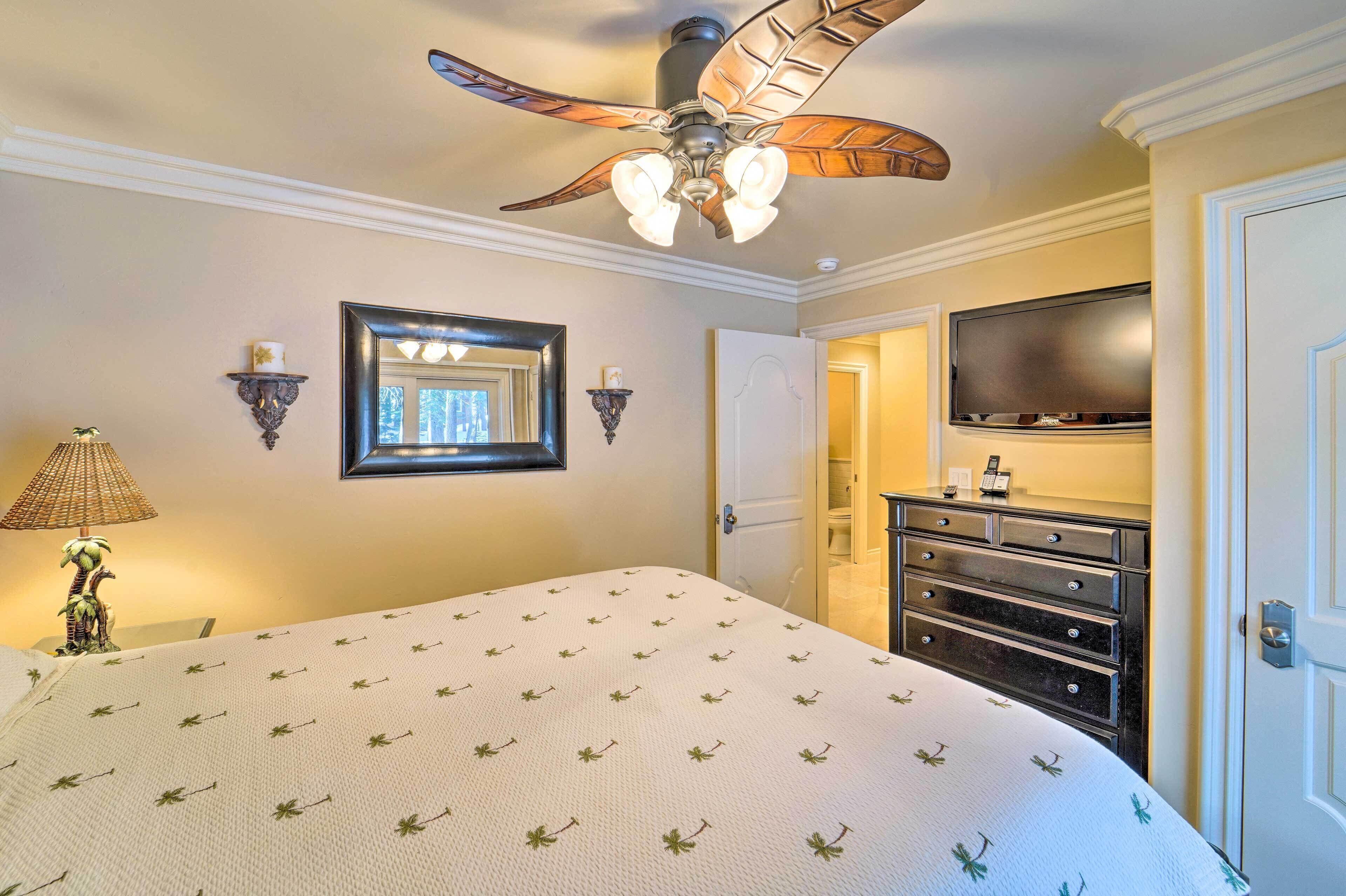 A bedroom with a bed, a ceiling fan, a TV, and a dresser.