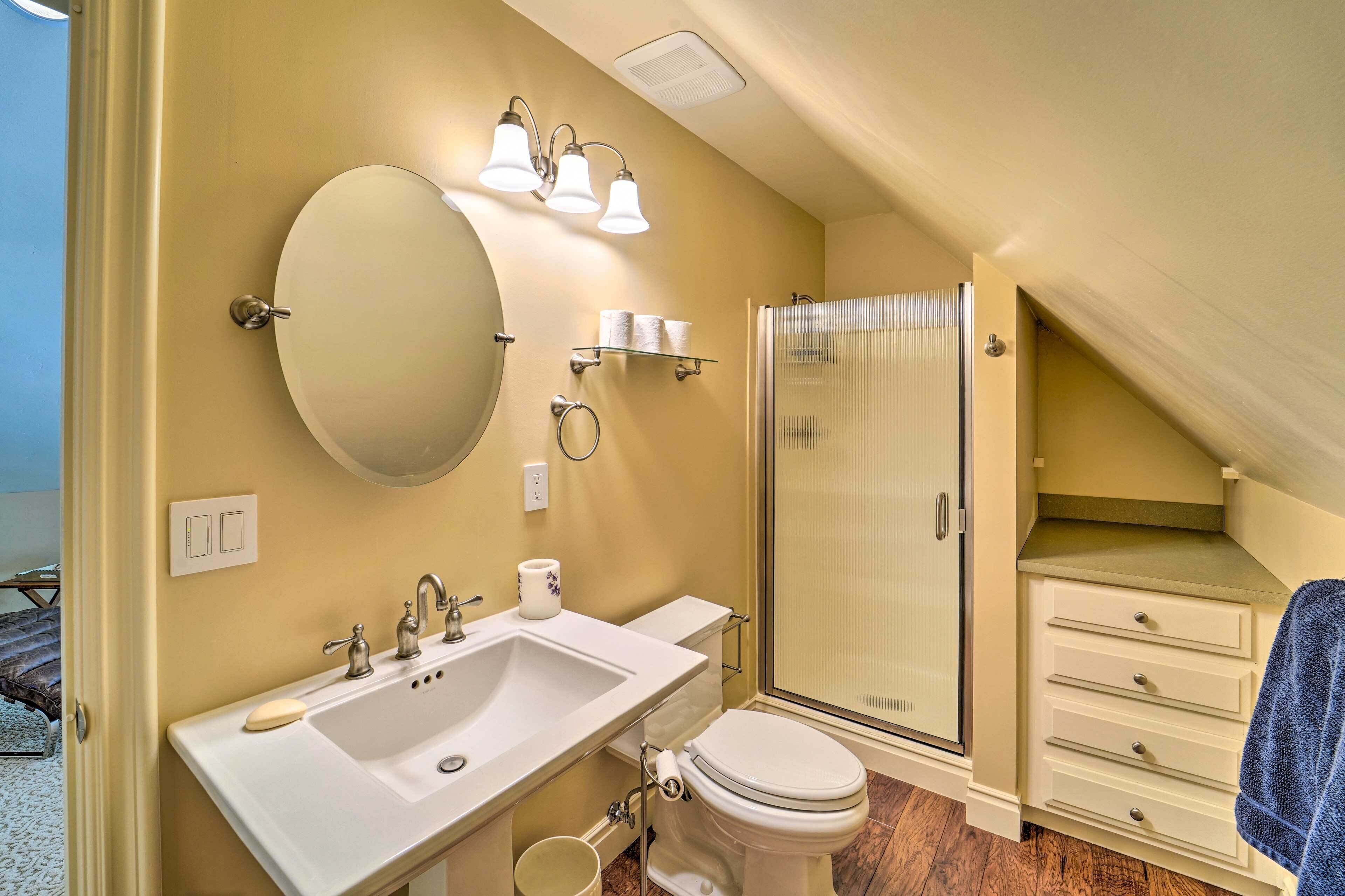 Une salle de bain équipée d’un lavabo, d’un miroir, de toilettes et d’une douche.