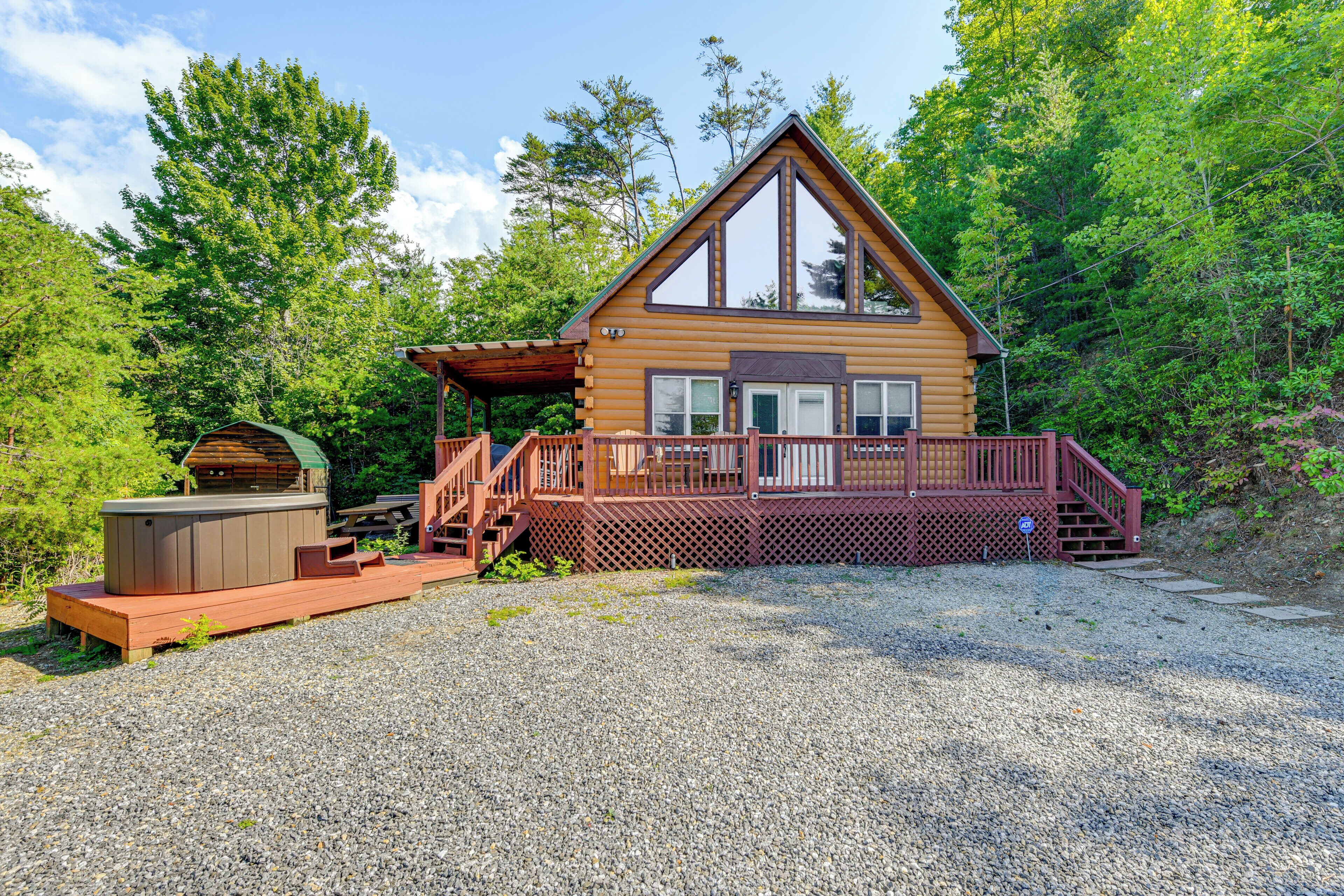 A cabin with a deck, a hot tub, and a picnic table.