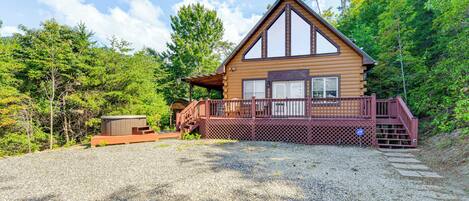 A log cabin with a wooden deck and a small shed.