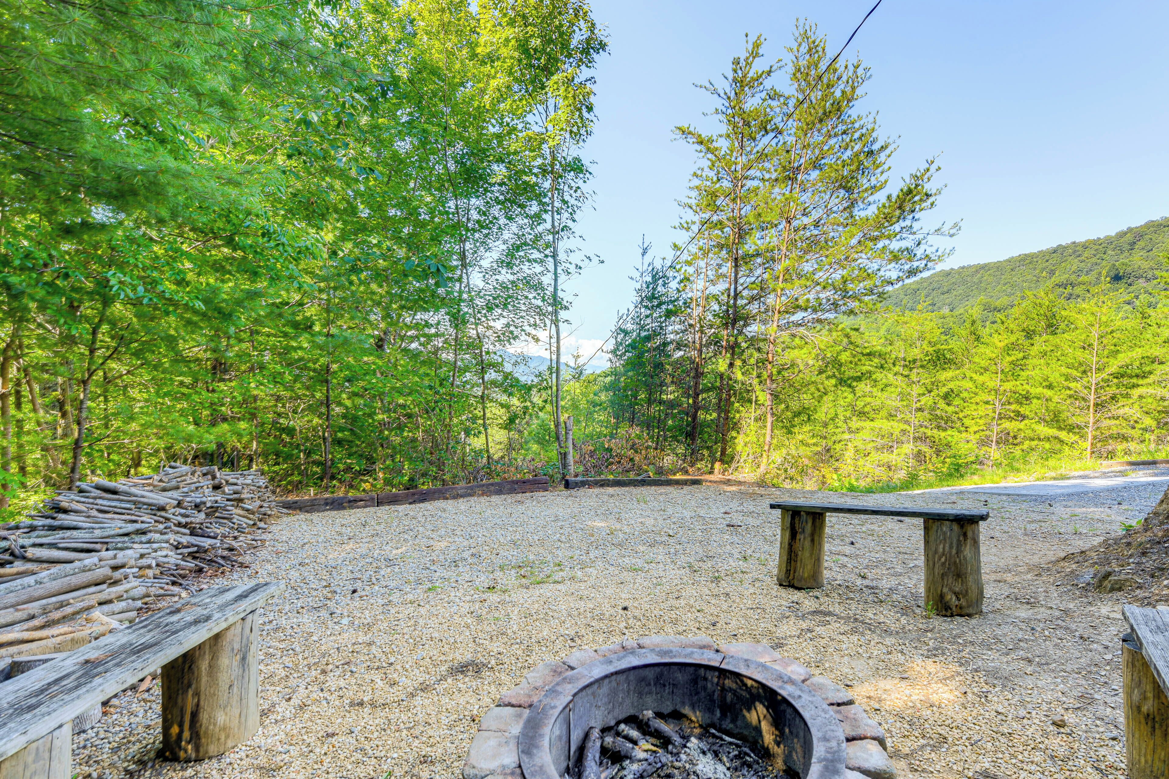 A campground with a fire pit, benches, and a gravel path.