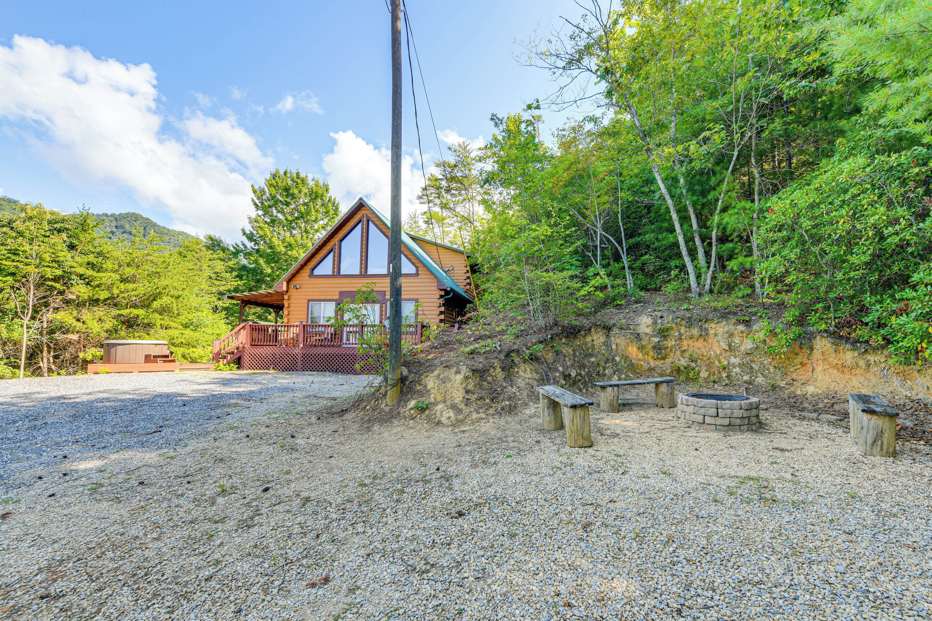 A cabin with a wooden exterior, a deck, and a gravel driveway.