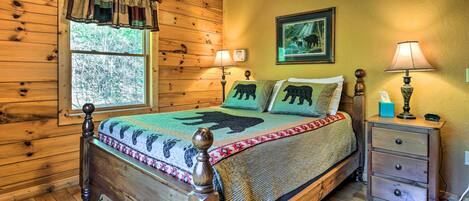 A wooden cabin bedroom with a bed, two bedside tables, a window, and a wall-mounted picture.