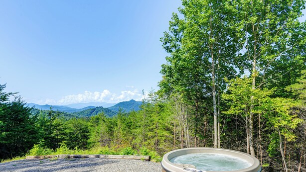 Ein Whirlpool in einer natürlichen Umgebung mit Blick auf Berge und Bäume.