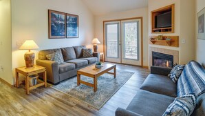 A living room with a sofa, coffee table, and lamps. There is a fireplace and a television mounted above it. - Resort-style Klamath Falls Home, Golf Course View! (Klamath Falls)