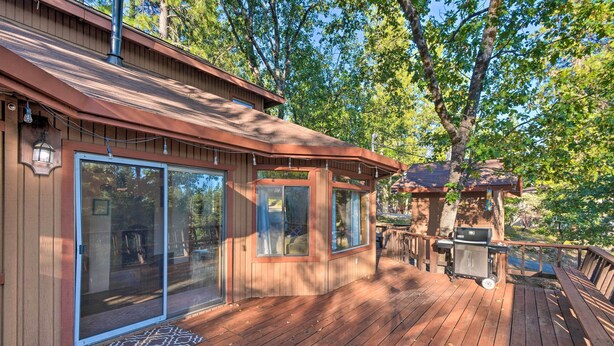 Une terrasse en bois équipée d’un barbecue, de portes-fenêtres coulissantes et d’un espace patio couvert.