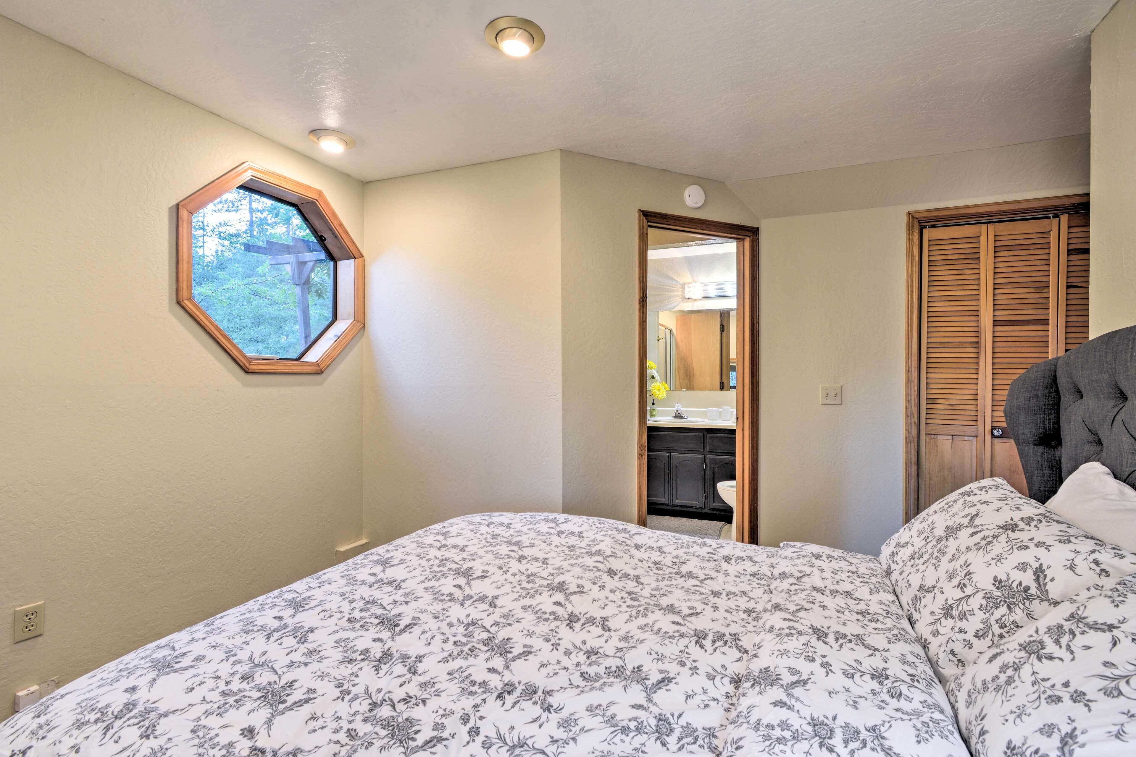 A bedroom with a bed, a window, a door, and a ceiling light.