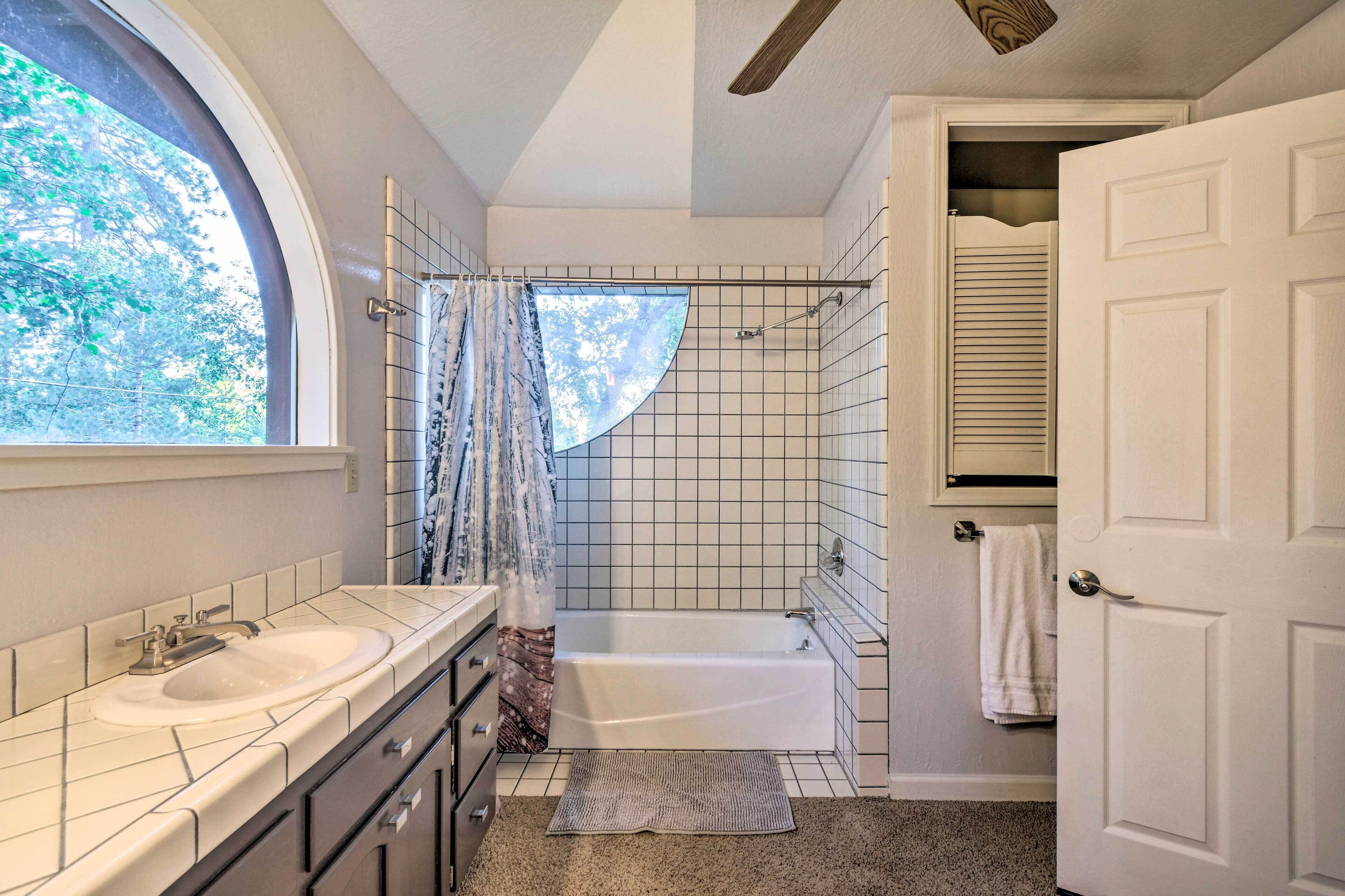A bathroom with a bathtub, a window, a shower curtain, and a towel rack.