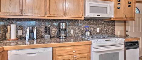 A kitchen with wooden cabinets, a microwave, a stove, and a dishwasher.