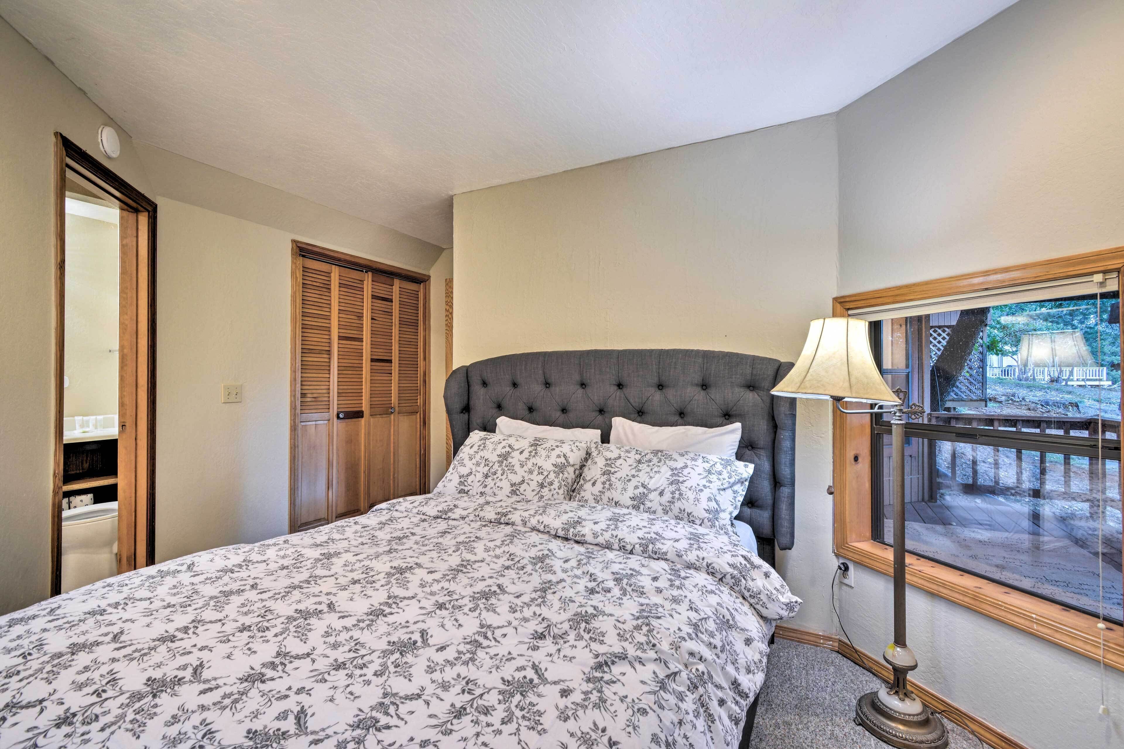 Una camera da letto con una testiera trapuntata, un letto con biancheria da letto floreale, una lampada da comodino e una finestra vista su una terrazza.