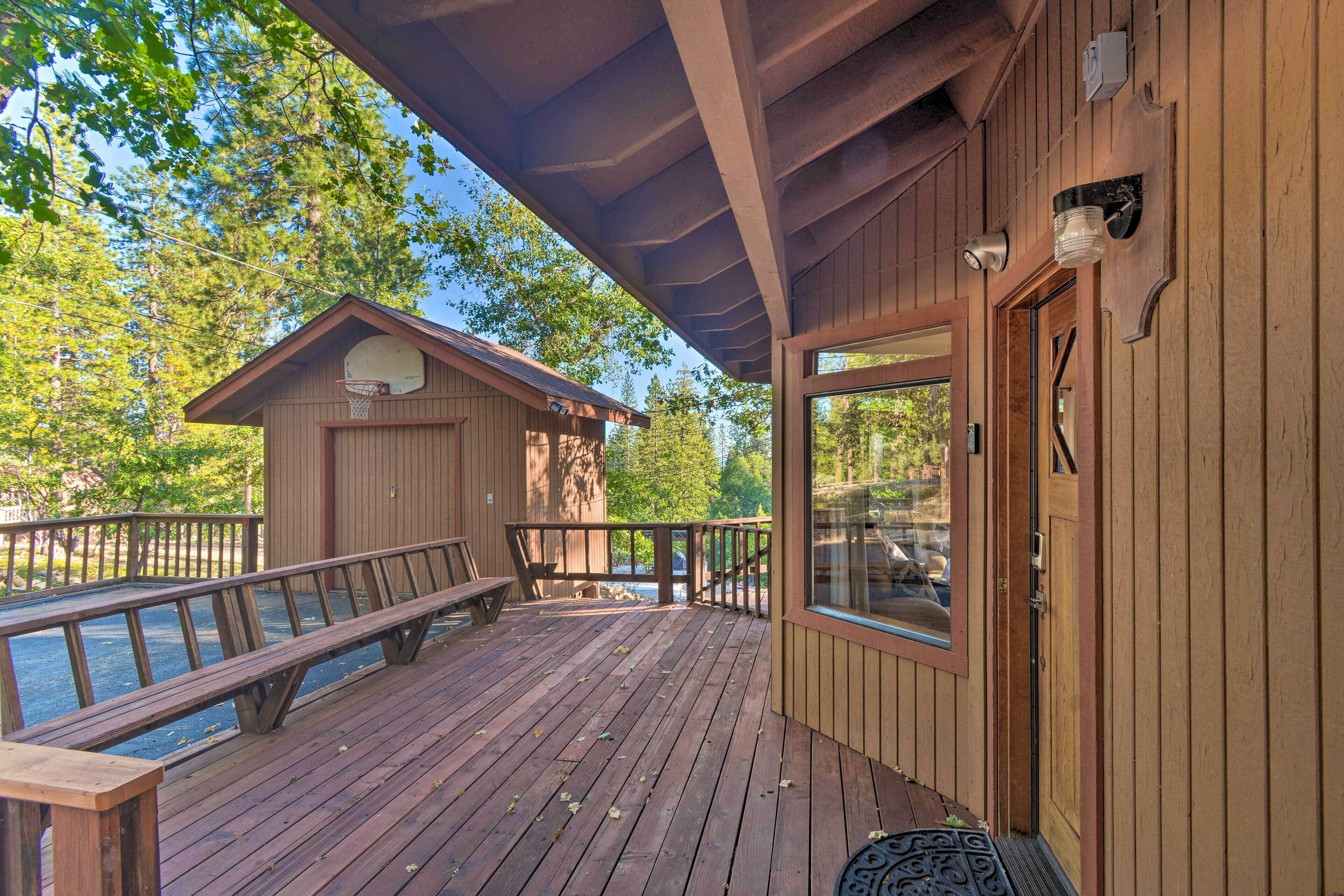 A wooden deck with a basketball hoop, a bench, and a door with a window.