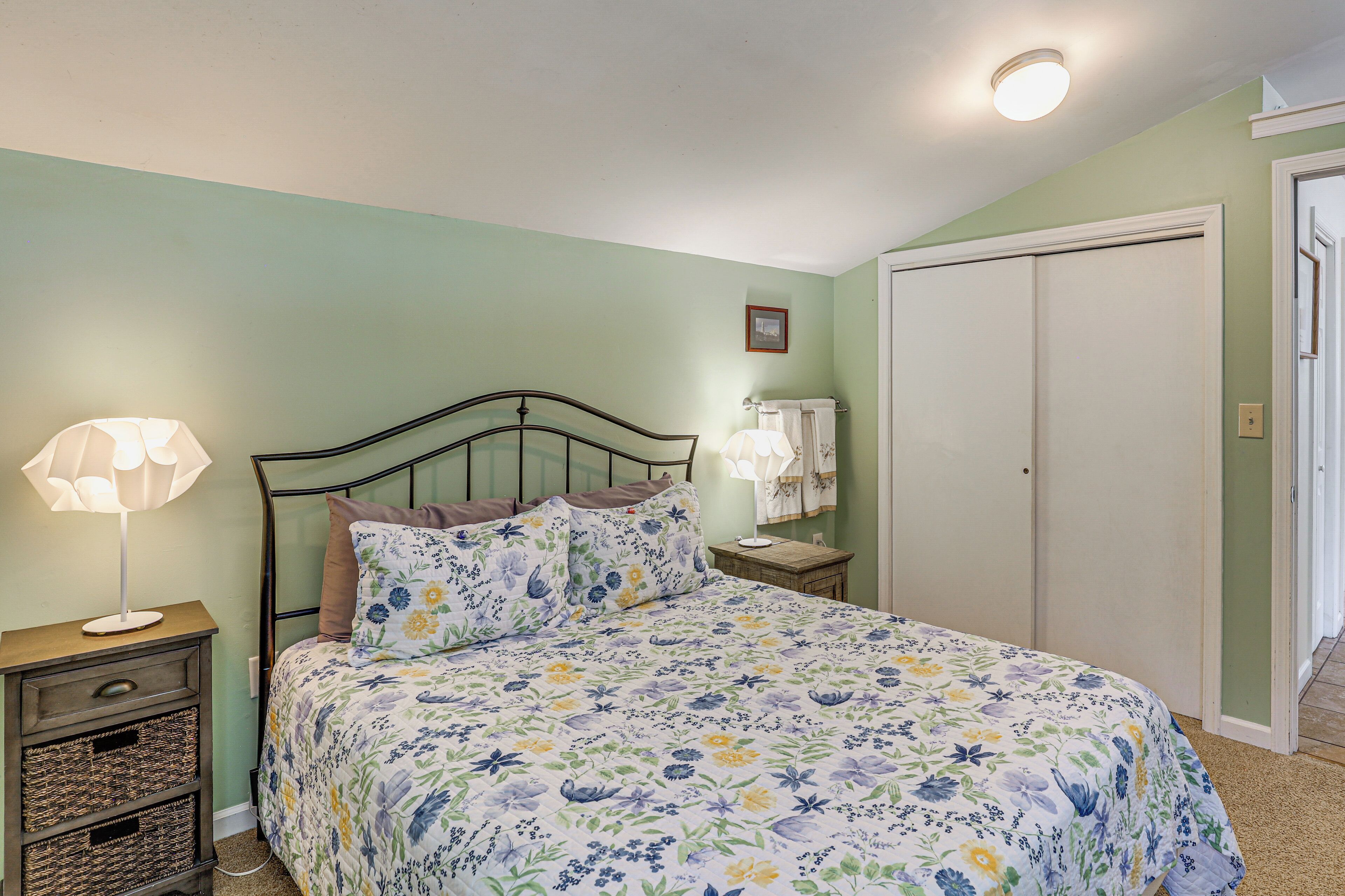 A bedroom with a bed, bedside lamps, a nightstand, and a closet.