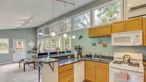 A kitchen with wooden cabinets, a white stove, and a large window. - Blue Ridge Retreat w/ Deck: Hike, Sip & Explore! (Asheville)