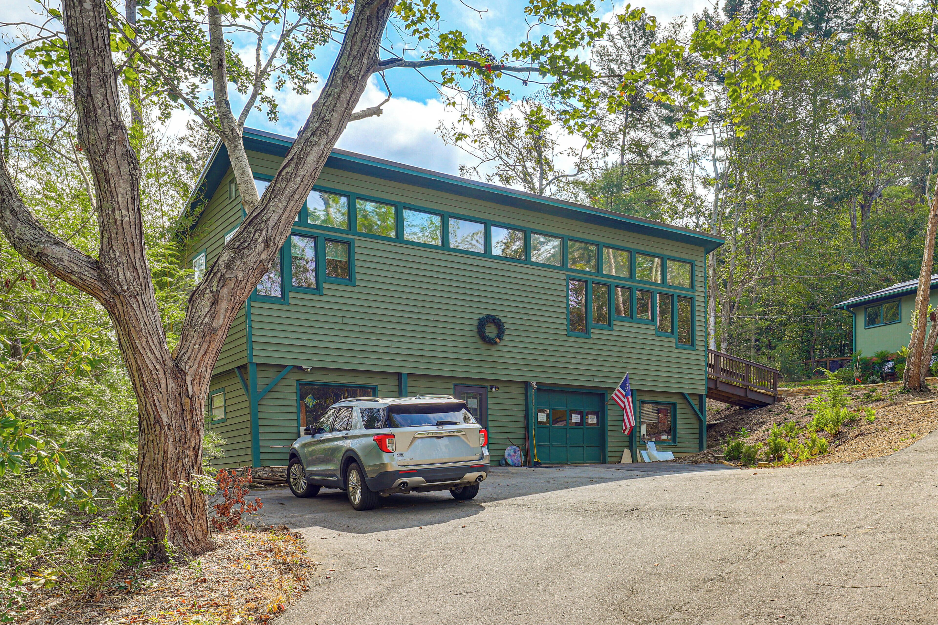 A two-story building with a green exterior and a parked car in front.