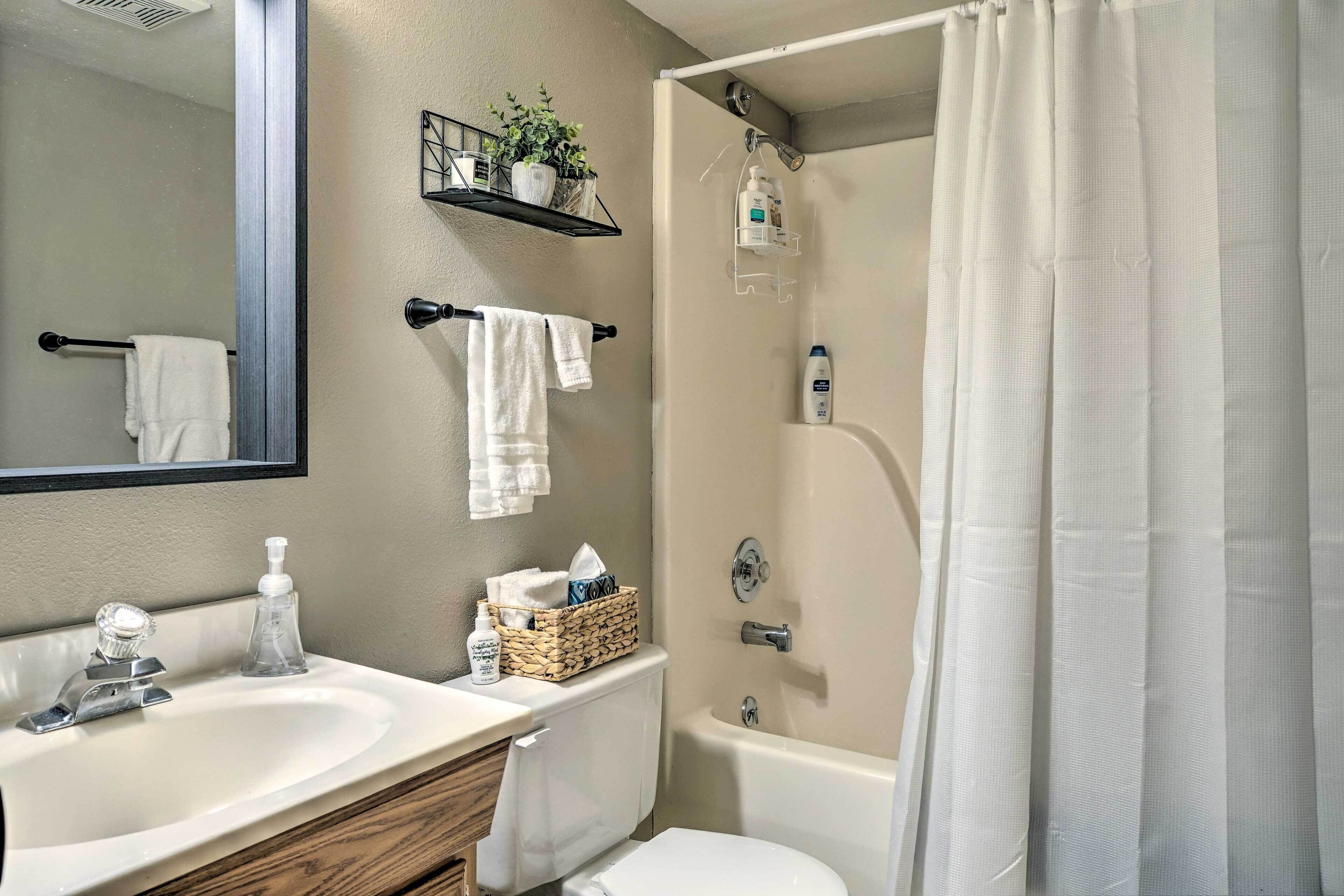 A bathroom with a sink, mirror, towel rack, shower, and toilet.