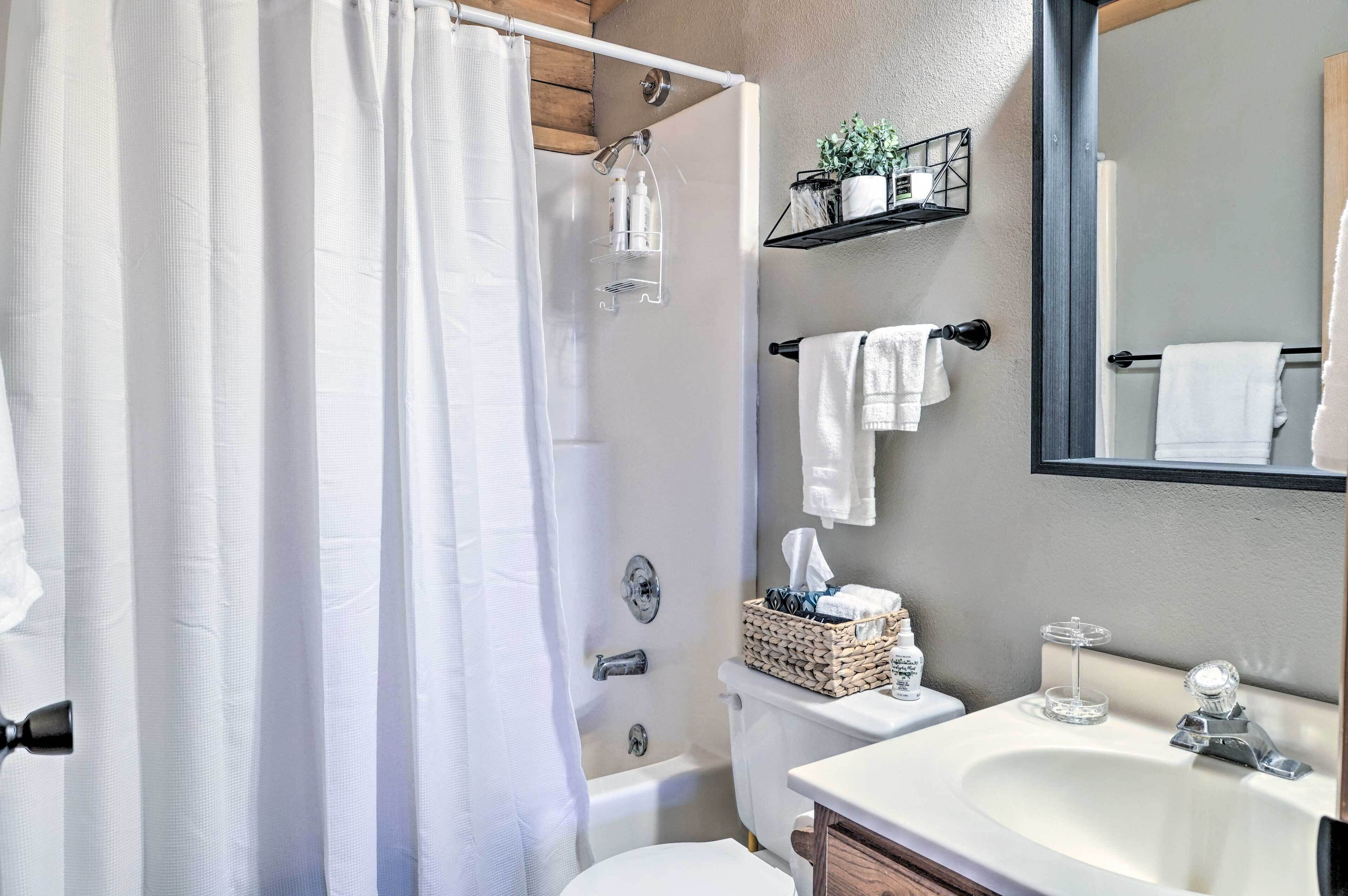 A bathroom with a shower, toilet, sink, and towel rack.