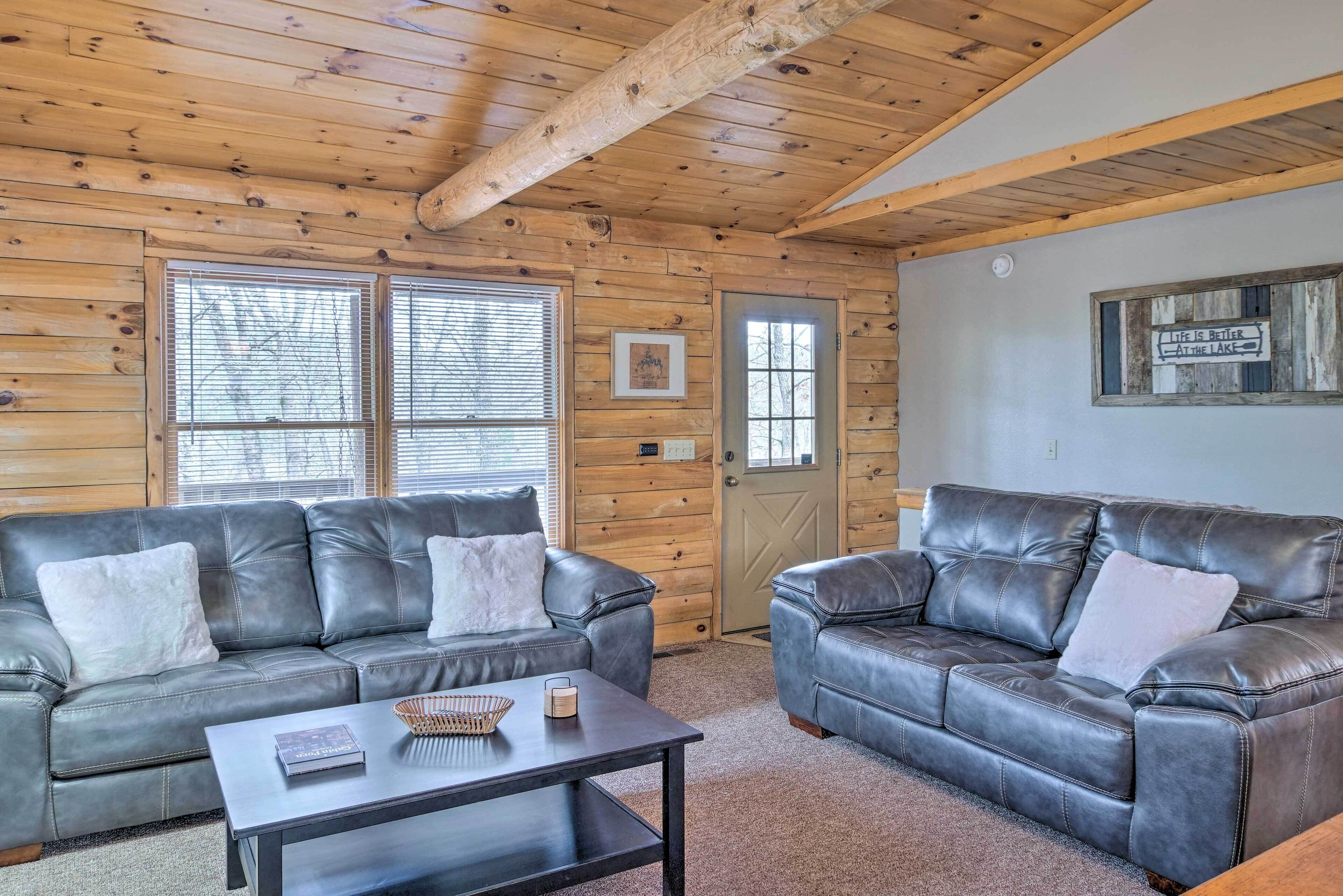A cozy room with two leather sofas, a coffee table, and wooden walls.