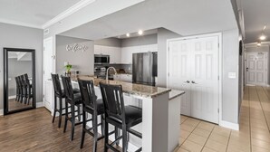 Una cocina moderna con armarios blancos, encimera de granito y electrodomésticos de acero inoxidable.