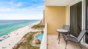 Un balcón con vista a la playa y una piscina.