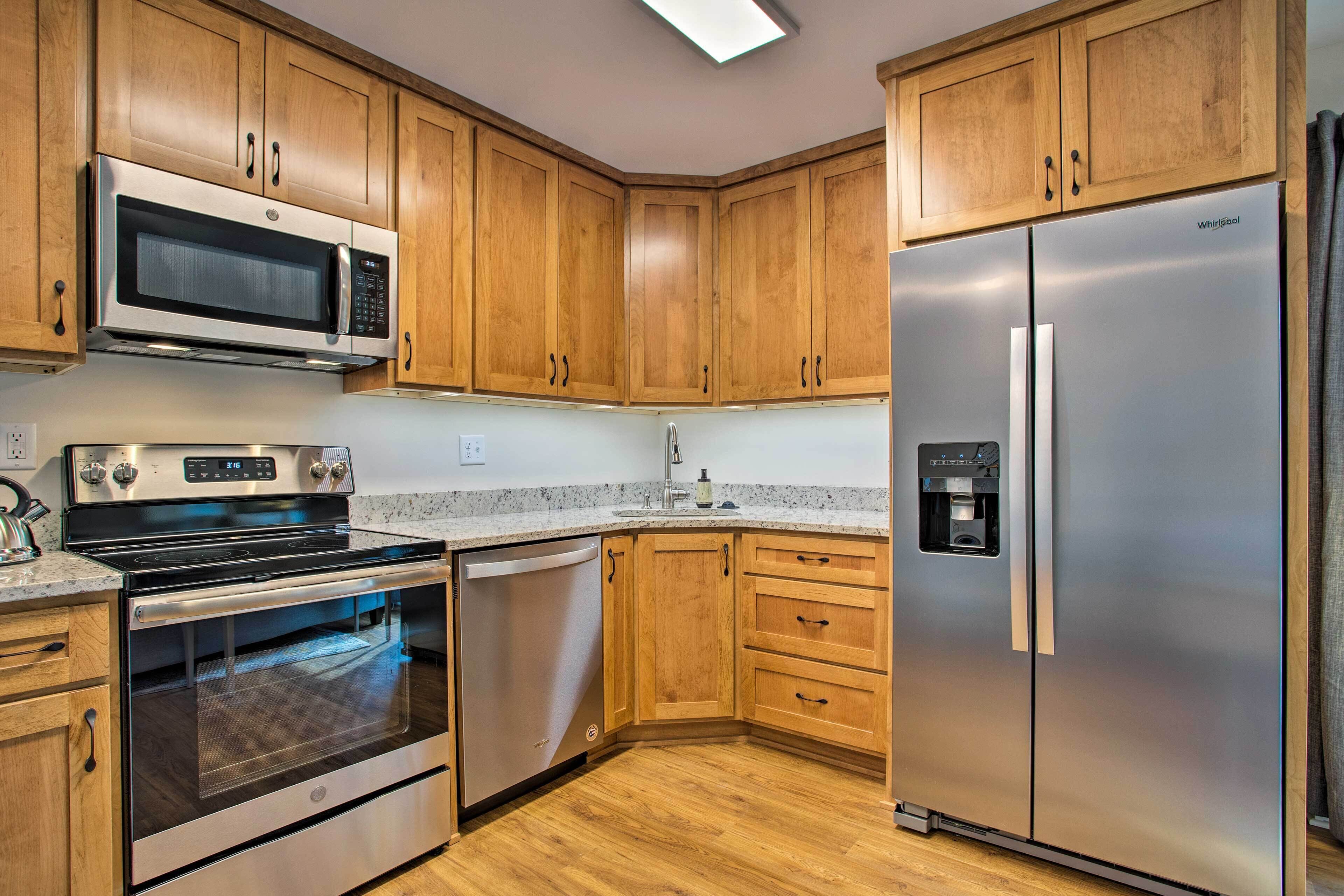 A kitchen with wooden cabinets, stainless steel appliances including a microwave, oven, dishwasher, and refrigerator.