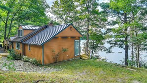 A cabin with a sloped roof, a front porch, and a view of a lake. - Beautiful Embden Pond Cabin w/ Dock & Kayaks! (North Anson)