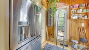 A kitchen with a stainless steel refrigerator, a water dispenser, and a wooden interior. - Beautiful Embden Pond Cabin w/ Dock & Kayaks! (North Anson)