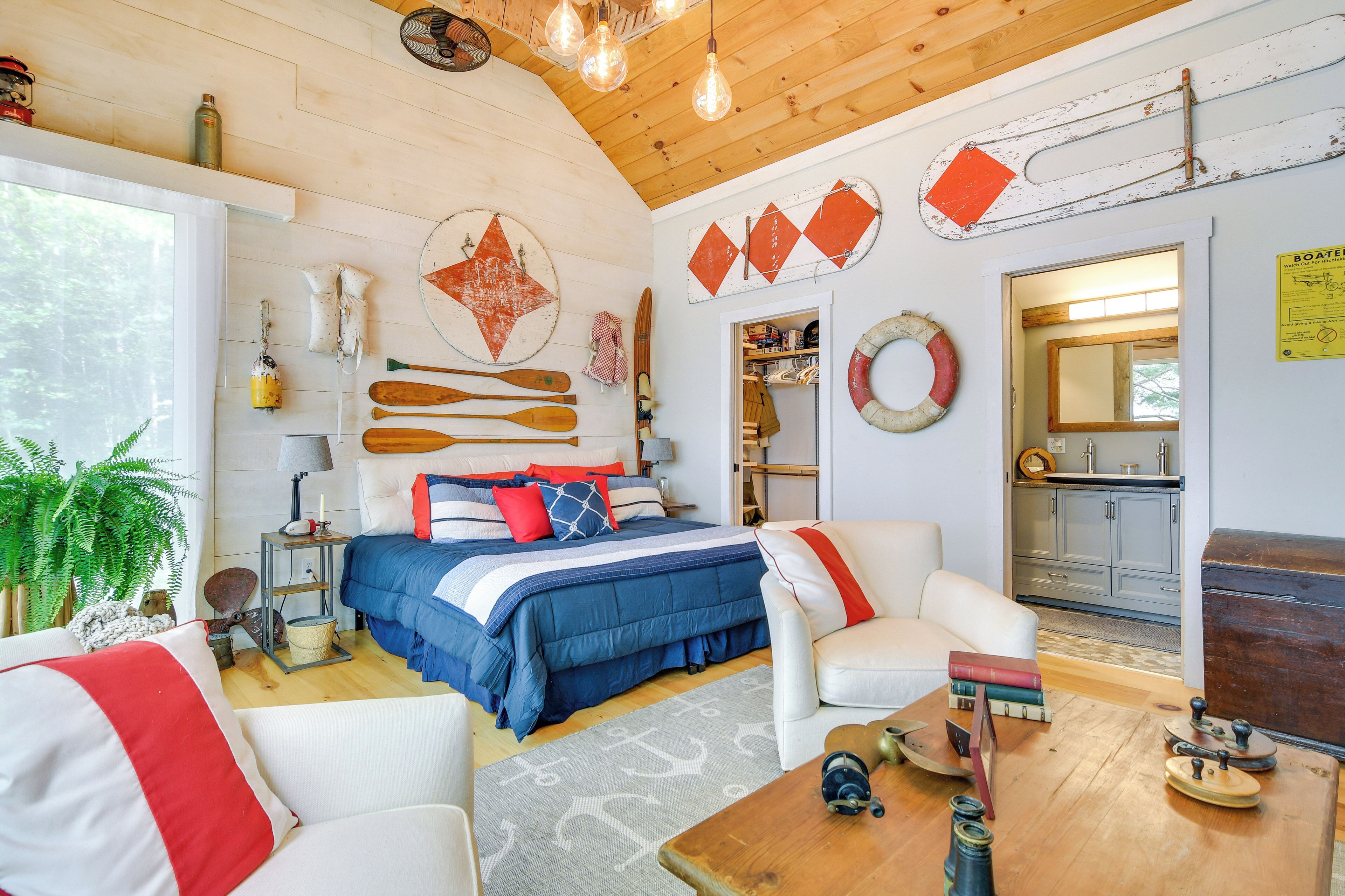 A cozy room with a bed, a white armchair, a wooden coffee table, and nautical decor.