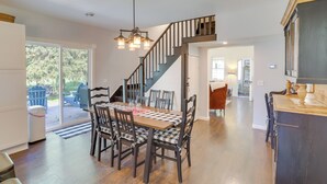 A spacious kitchen with a wooden dining table, dark wooden chairs, and a staircase leading to another level. - South Haven Farmhouse w/ Fire Pit, 4 Mi to Beach! (South Haven)