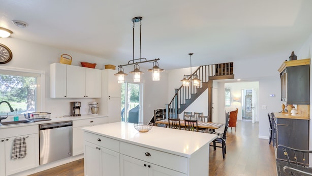 A spacious kitchen with white cabinetry, a central island, and a staircase leading to another level. - South Haven Farmhouse w/ Fire Pit, 4 Mi to Beach! (South Haven)