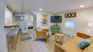 A living room with a sofa, chairs, a small table, a television, and a green cabinet. - Cozy Ventnor Getaway: Walk to Public Beach! (Ventnor City)