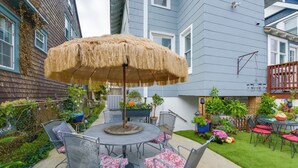 A patio with a round table, chairs, and a thatched umbrella. - Cozy Ventnor Getaway: Walk to Public Beach! (Ventnor City)