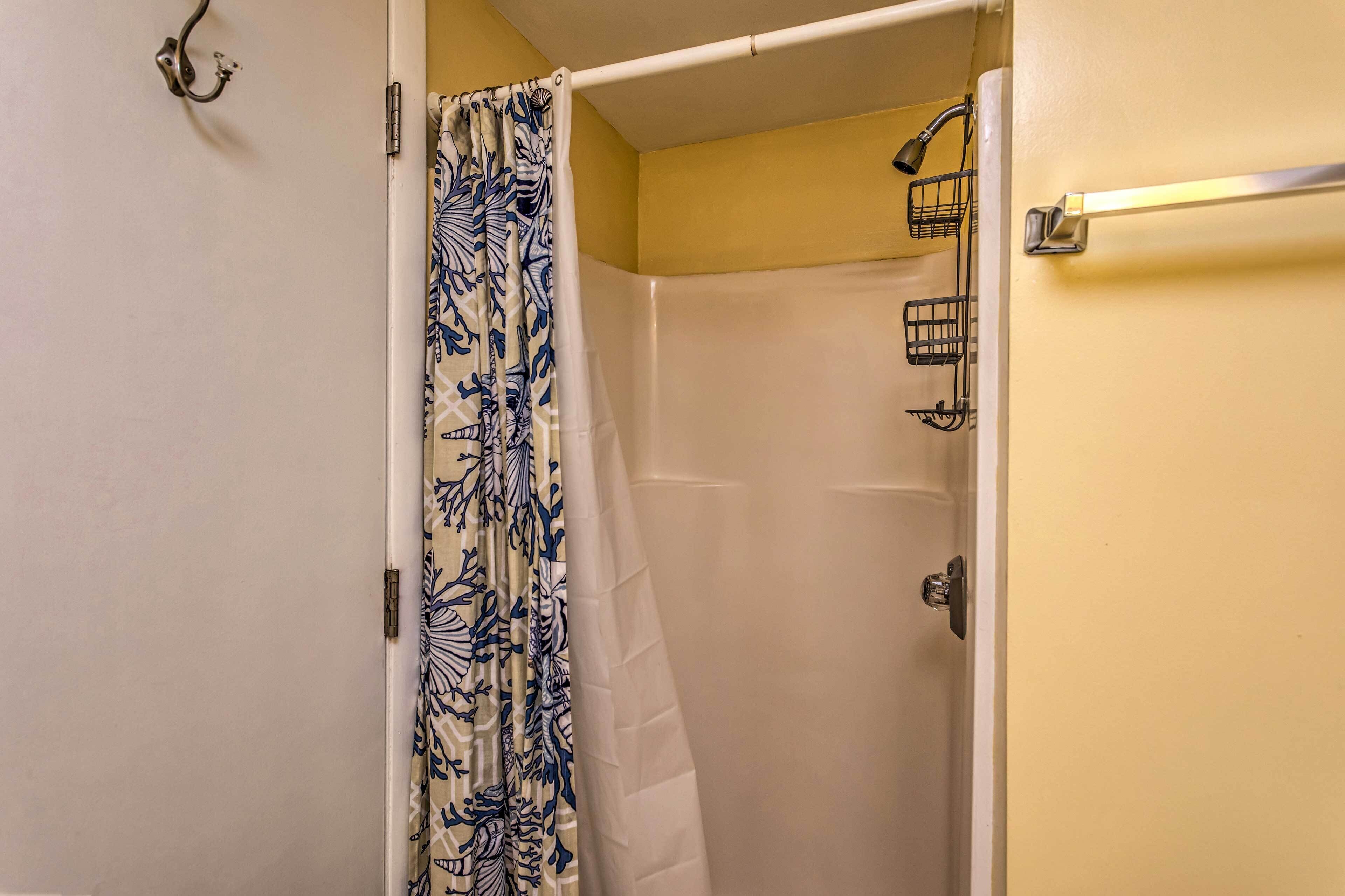 Une salle de bain avec un rideau de douche, un porte-serviettes et un autre porte-serviettes fixé au mur.
