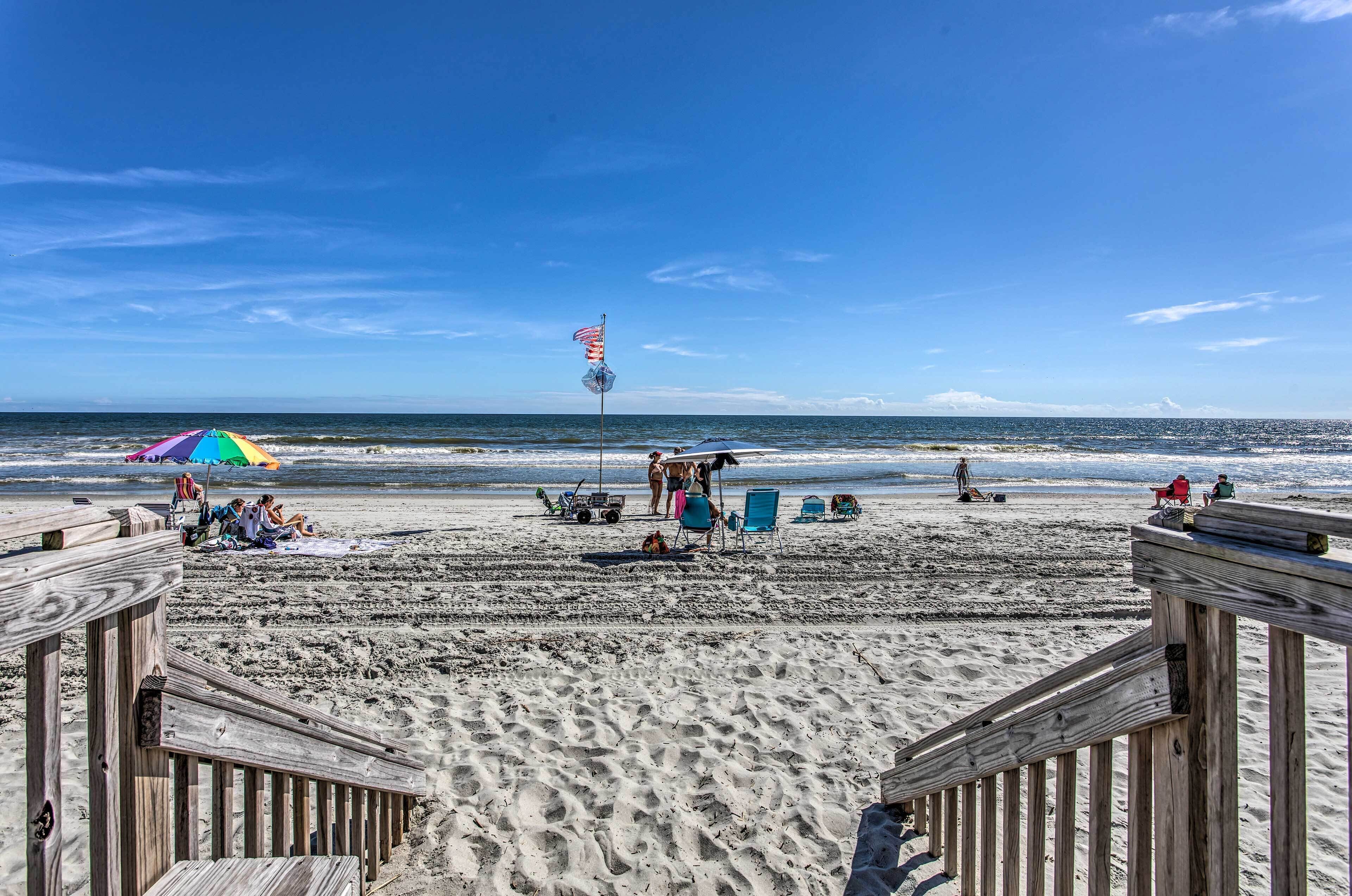Une plage avec une promenade en bois, des parasols et des chaises de plage.