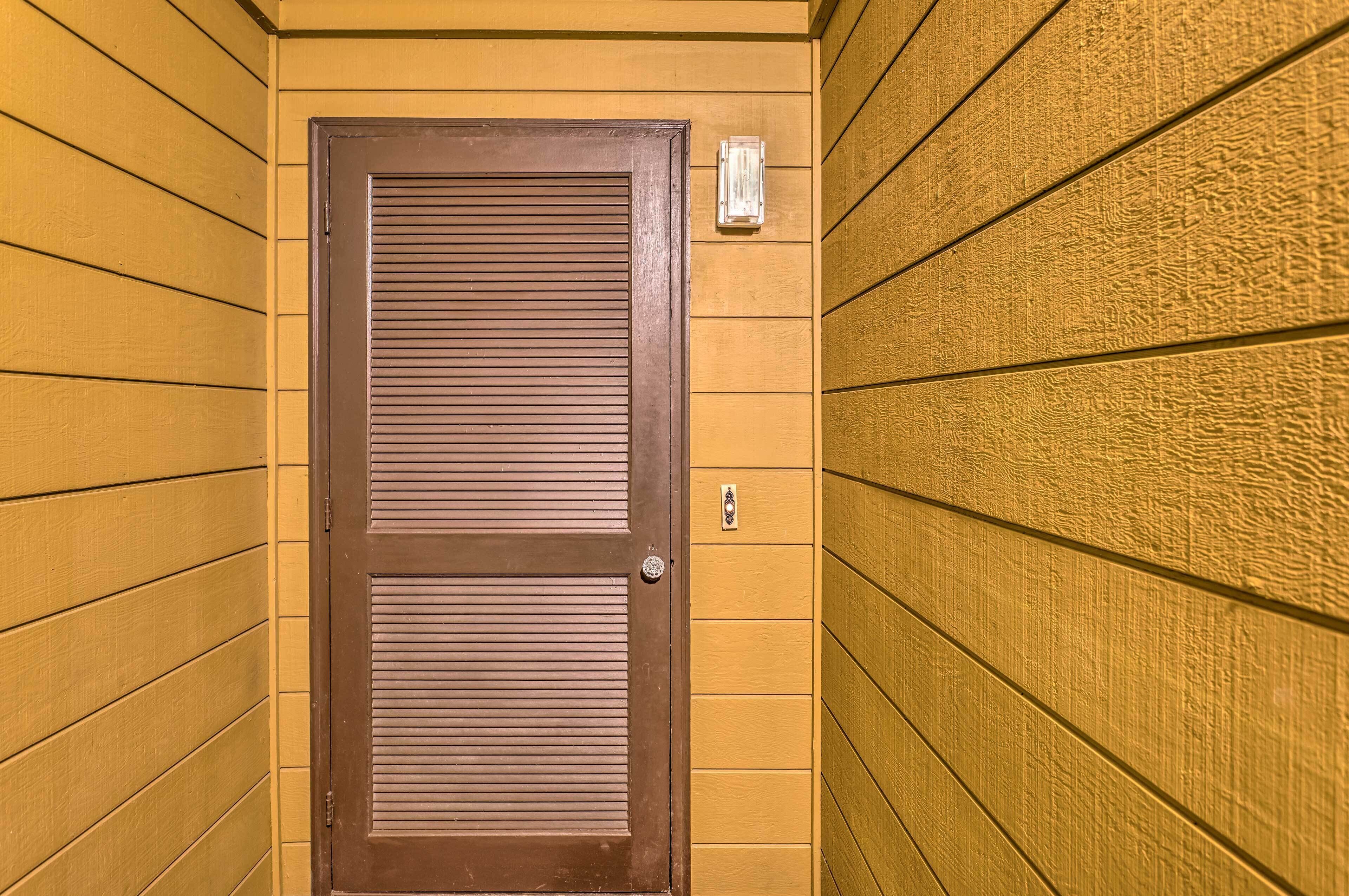 A wooden door with a window, set in a hallway with wooden walls.