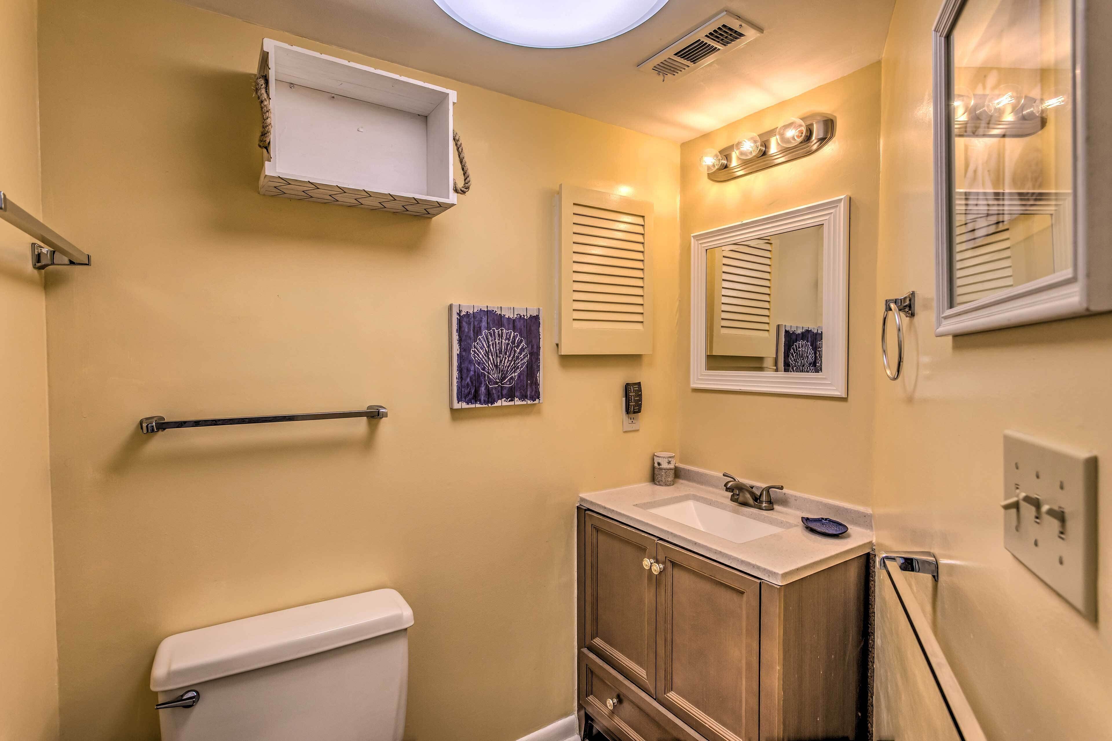 A bathroom with a toilet, sink, vanity, towel rack, and a mirror.