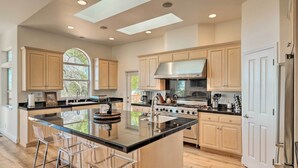 Una cocina amplia con una isla grande, armarios de madera y una estufa de acero inoxidable.