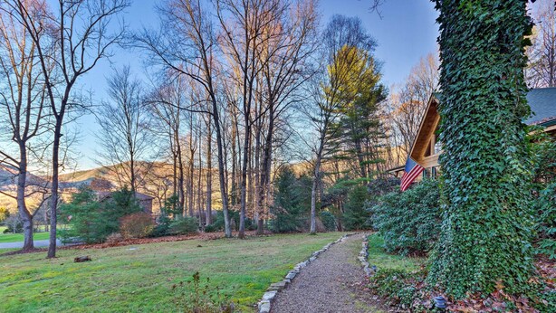 A pathway leading to a house surrounded by trees and a grassy area.